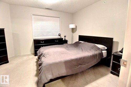 Neutral-toned bedroom featuring wall-to-wall carpeting and an overhead light fixture - 413 279 Suder Greens Drive, Edmonton, AB - Indoor Photo Showing Bedroom