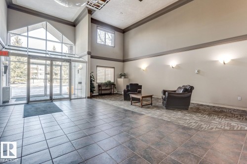 Spacious lobby featuring large format tile flooring, a vaulted ceiling, and an expansive glass entryway - 413 279 Suder Greens Drive, Edmonton, AB - Indoor Photo Showing Other Room