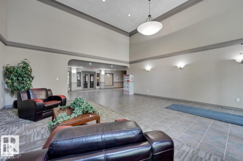 Spacious common area featuring high ceilings, neutral wall tones, contrasting trim, a mix of patterned carpet and large format tile flooring, and a contemporary pendant light fixture - 413 279 Suder Greens Drive, Edmonton, AB - Indoor