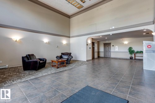 Spacious common area featuring neutral wall tones, sconce lighting, and tile flooring - 413 279 Suder Greens Drive, Edmonton, AB - Indoor Photo Showing Other Room