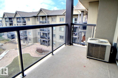 Concrete balcony with glass panel railings and dark metal framing - 413 279 Suder Greens Drive, Edmonton, AB - Outdoor