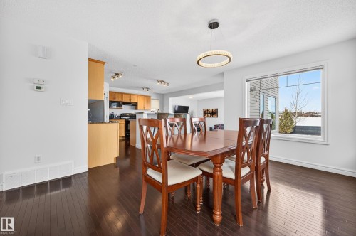 Dining area featuring dark wood-finish flooring and a contemporary ring chandelier - 8477 Sloane Crescent, Edmonton, AB - Indoor Photo Showing Dining Room