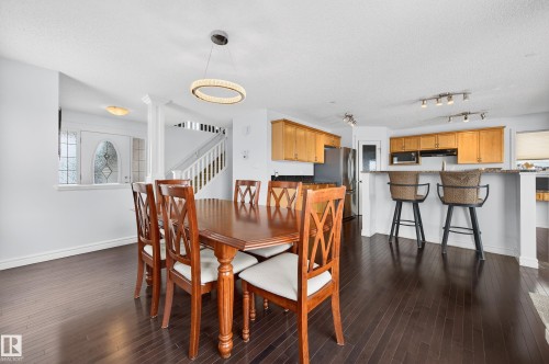 Open-concept layout featuring dark wood-finish flooring, a modern circular pendant light, and recessed lighting - 8477 Sloane Crescent, Edmonton, AB - Indoor Photo Showing Dining Room