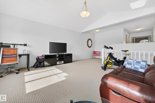 Spacious loft area featuring neutral carpeting, white walls, and a white railing overlooking the space below - 8477 Sloane Crescent, Edmonton, AB - Indoor