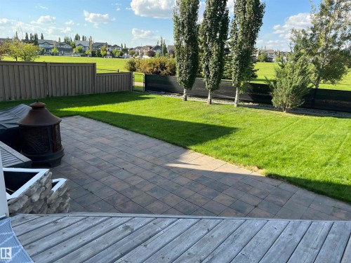 Expansive backyard featuring a paver patio, a manicured lawn, and mature trees lining the property boundary - 8477 Sloane Crescent, Edmonton, AB - Outdoor
