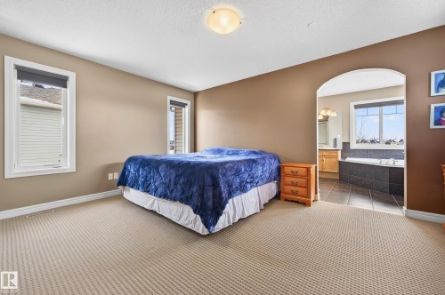 Spacious bedroom featuring neutral carpeting and two windows with white trim - 8477 Sloane Crescent, Edmonton, AB - Indoor Photo Showing Bedroom