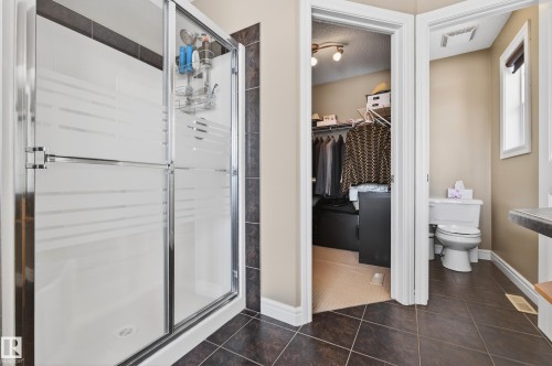 Frosted glass shower enclosure with chrome hardware and dark tile surround - 8477 Sloane Crescent, Edmonton, AB - Indoor Photo Showing Bathroom
