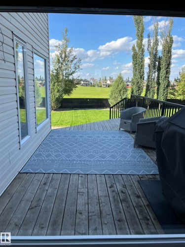 Exterior deck featuring wood planking, black railings, and a direct sightline to a large grassy expanse - 8477 Sloane Crescent, Edmonton, AB - Outdoor