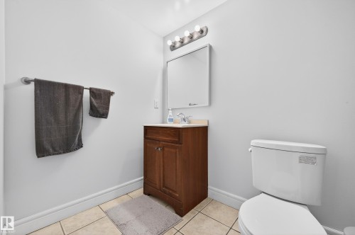 Bathroom featuring a wood-finish vanity with a light-colored countertop, an undermount sink, and a chrome faucet - 8477 Sloane Crescent, Edmonton, AB - Indoor Photo Showing Bathroom