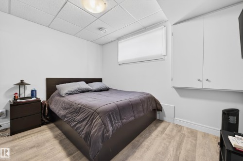 Bedroom featuring a drop ceiling with recessed lighting, light wood-finish flooring, and a window with a roller shade - 8477 Sloane Crescent, Edmonton, AB - Indoor Photo Showing Bedroom