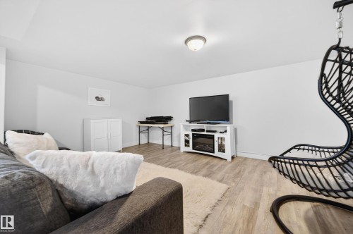 Spacious room featuring light wood-finish flooring, white walls, and a flush-mount ceiling light fixture - 8477 Sloane Crescent, Edmonton, AB - Indoor