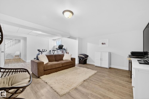 Spacious lower-level area featuring wood-finish flooring, white walls, and recessed lighting - 8477 Sloane Crescent, Edmonton, AB - Indoor Photo Showing Living Room
