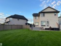 Expansive backyard featuring a manicured lawn, full fencing, and a multi-level stone patio with black metal railings - 8477 Sloane Crescent, Edmonton, AB  - Outdoor 