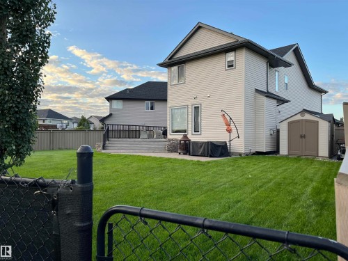 Expansive green lawn with a two-story home featuring light-colored siding and dark roof - 8477 Sloane Crescent, Edmonton, AB - Outdoor With Exterior
