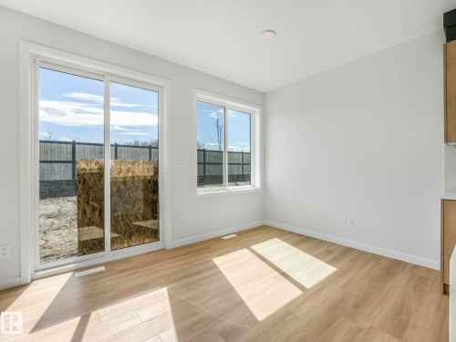 Bright interior space featuring wood-finish flooring and white walls - 272 Munn Way, Leduc, AB - Indoor Photo Showing Other Room With Fireplace