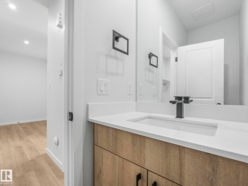 Modern vanity featuring a wood-finish cabinet, white countertop, and integrated rectangular sink - 272 Munn Way, Leduc, AB - Indoor Photo Showing Bathroom
