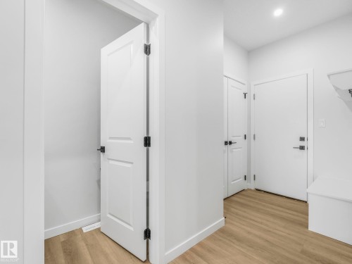 Entryway featuring wood-finish flooring, white paneled doors with matte black hardware, recessed lighting, and a built-in bench - 272 Munn Way, Leduc, AB - Indoor Photo Showing Other Room