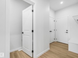 Entryway featuring wood-finish flooring, white paneled doors with matte black hardware, recessed lighting, and a built-in bench - 