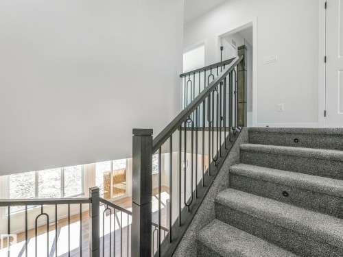 Carpeted staircase with integrated step lighting and metal balusters - 272 Munn Way, Leduc, AB - Indoor Photo Showing Other Room