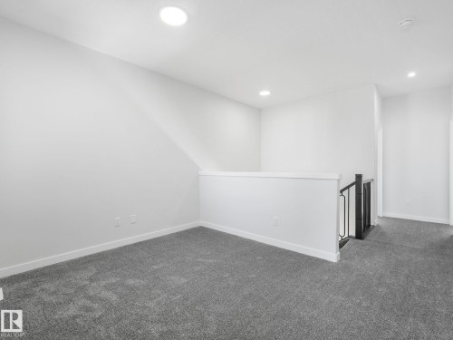Carpeted loft area featuring recessed lighting, white walls, and a contemporary black and white banister - 272 Munn Way, Leduc, AB - Indoor Photo Showing Other Room