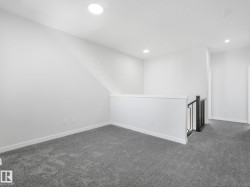Carpeted loft area featuring recessed lighting, white walls, and a contemporary black and white banister - 