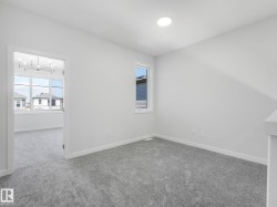 Neutral gray carpet throughout, white painted walls, and a single window with white trim - 