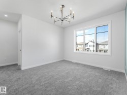 Spacious room featuring gray carpeting, a large multipane window, a contemporary black and gold chandelier, and recessed lighting - 