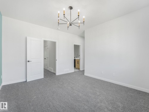 Spacious room featuring neutral carpeting and a modern chandelier - 272 Munn Way, Leduc, AB - Indoor Photo Showing Other Room