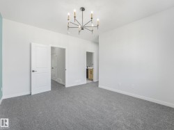 Spacious room featuring neutral carpeting and a modern chandelier - 