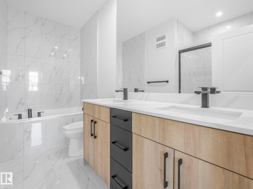Dual vanity featuring wood-finish cabinetry, black drawer fronts, and matte black hardware - 272 Munn Way, Leduc, AB - Indoor Photo Showing Bathroom