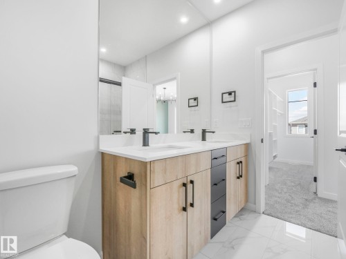 Contemporary bathroom featuring a dual vanity with wood-finish and dark cabinetry, quartz countertops, and matte black fixtures - 272 Munn Way, Leduc, AB - Indoor Photo Showing Bathroom
