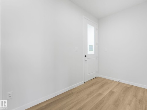 Interior room featuring a white door with a clear glass insert, light wood-finish flooring, and white baseboards - 272 Munn Way, Leduc, AB - Indoor Photo Showing Other Room