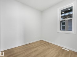 Room featuring light wood-finish flooring, white walls, and a single window with white trim - 