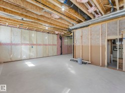 Unfinished basement with exposed wood joists and subflooring, insulated walls, and concrete flooring - 
