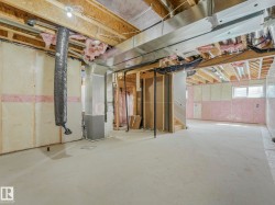 Spacious unfinished lower level featuring exposed ceiling joists, substantial ductwork, and insulated walls - 
