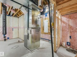 Unfinished basement with exposed wood framing, concrete flooring, and visible insulation - 