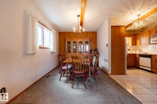 Dining area featuring a wood-finish accent wall and exposed ceiling beams - 8612 68A Street, Edmonton, AB - Indoor