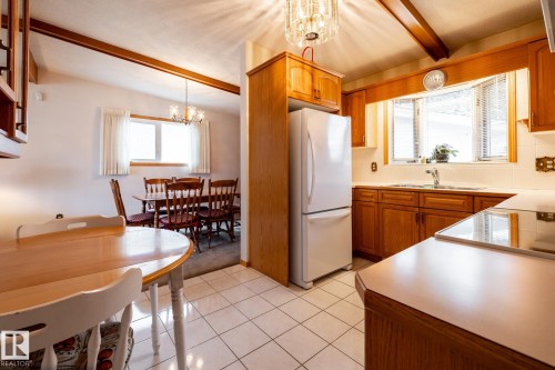Kitchen featuring wood cabinetry, white tile flooring, and integrated appliances - 8612 68A Street, Edmonton, AB - Indoor Photo Showing Other Room