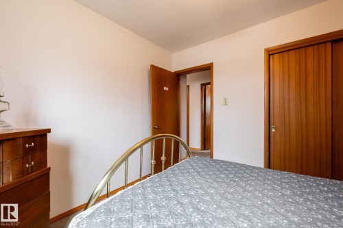 Room featuring a brass-finish bed frame, wood-finish sliding closet doors, a wood-finish dresser, and carpeted flooring - 8612 68A Street, Edmonton, AB - Indoor Photo Showing Bedroom