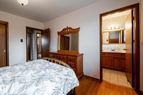 Bedroom featuring polished wood-finish flooring and a crystal-style flush-mount ceiling fixture - 8612 68A Street, Edmonton, AB - Indoor Photo Showing Bedroom