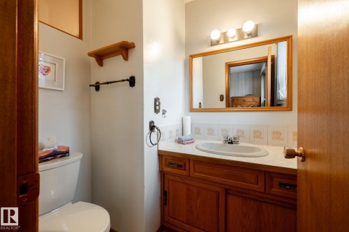 Vanity with a wood-finish cabinet, integrated sink, and laminate countertop - 8612 68A Street, Edmonton, AB - Indoor Photo Showing Bathroom