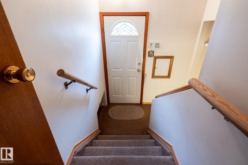 Carpeted stairs featuring light wood-finish handrails and trim - 8612 68A Street, Edmonton, AB - Indoor Photo Showing Other Room