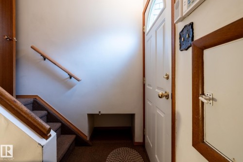 Entryway featuring a white paneled door with an arched window, wood-finish trim, brass hardware, and a security panel - 8612 68A Street, Edmonton, AB - Indoor Photo Showing Other Room