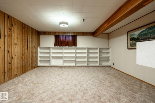 Finished room featuring built-in shelving, wood paneling, and wood ceiling beam accents - 8612 68A Street, Edmonton, AB - Indoor