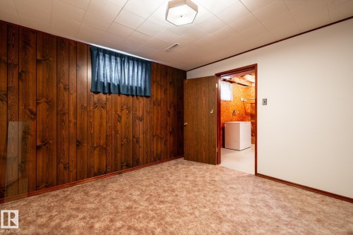 Finished interior space featuring wood-finish paneling, a drop ceiling, and a window with privacy covering - 8612 68A Street, Edmonton, AB - Indoor Photo Showing Other Room