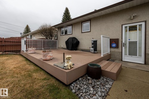 Spacious multi-level deck featuring composite decking and white railing, complimented by a concrete patio area and mature landscaping - 8612 68A Street, Edmonton, AB - Outdoor With Deck Patio Veranda With Exterior