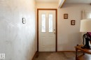 Entryway featuring a white door with decorative glass inserts and wood trim, complemented by textured wallpaper and carpet flooring - 8612 68A Street, Edmonton, AB  - Indoor Photo Showing Other Room 