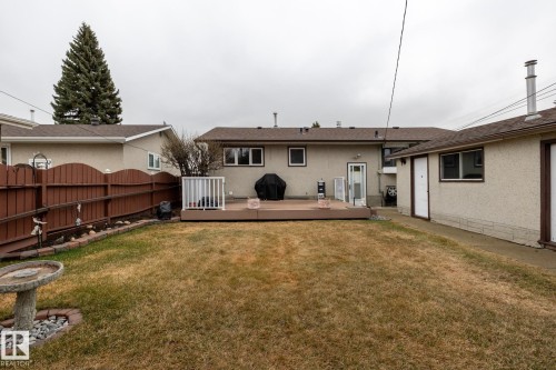 Rear exterior featuring a large wooden deck with white railing, stucco siding, and a brown privacy fence - 8612 68A Street, Edmonton, AB - Outdoor With Deck Patio Veranda With Exterior