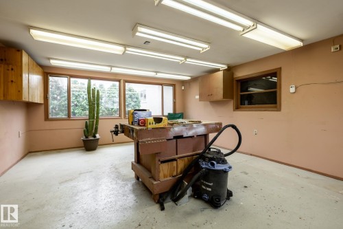Workshop space featuring concrete flooring, multiple fluorescent ceiling lights, and wood-finish cabinetry - 8612 68A Street, Edmonton, AB - Indoor