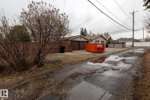 Detached garages with brown paneled doors and concrete driveways, bordered by wood fencing - 8612 68A Street, Edmonton, AB - Outdoor